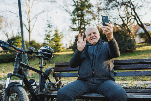 Man Using Cell Phone For Video Call While Seated on Park Bench