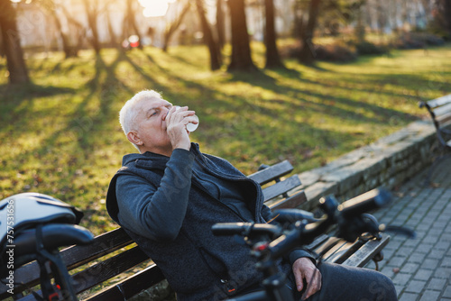 Man Sitting on a Park Bench Drinking From Coffee Cup