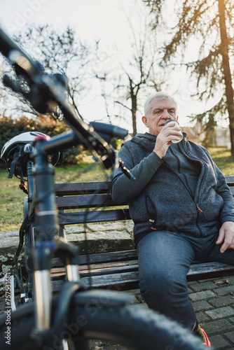 Man Enjoys Coffee While Resting With Bicycle on a Park Bench