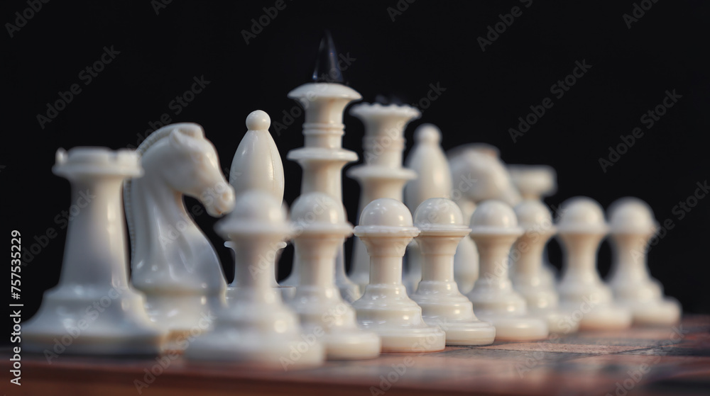 Close-up of white chess pieces along the board against a dark background. diagonal arrangement