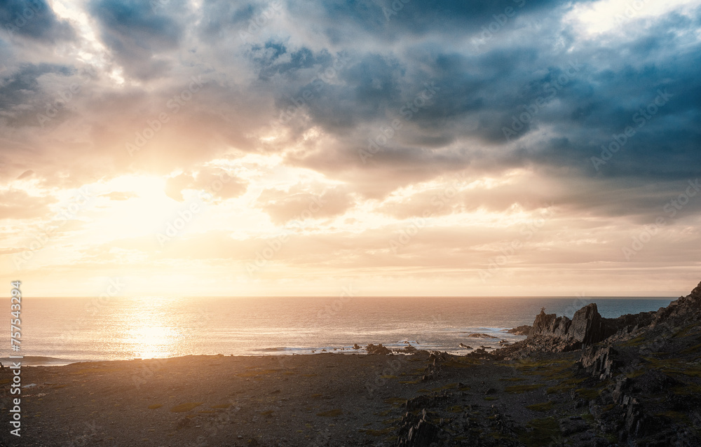 Dramatic scene with big rocks, sea, sunbeam and sundown Dramatic scene with big rocks, sea, sunbeam and sundown