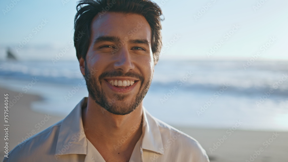 Portrait happy man model posing on sunny sea coast at evening. Handsome hipster  - obrazy, fototapety, plakaty 