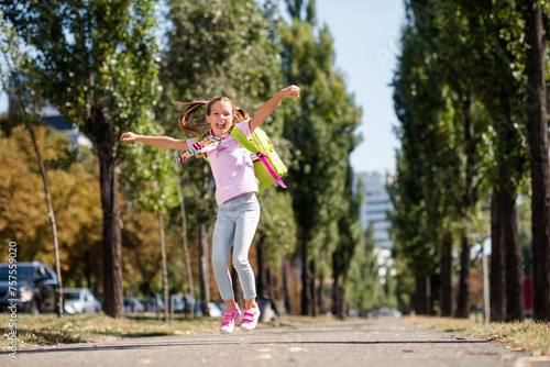 Photo portrait of ponytails cute small girl jumping excited shopping big sales dressed stylish garment elementary school student park
