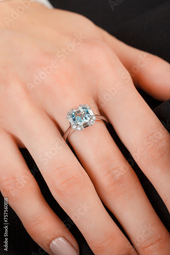 Beautiful female hand with gold ring with diamonds and emerald on gray background