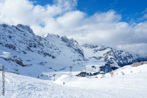 Winter sports enthusiasts descend the slopes at Engelberg  a Swiss Alps resort with snowcovered mountains  ski lifts  and varied terrain for all skill levels.