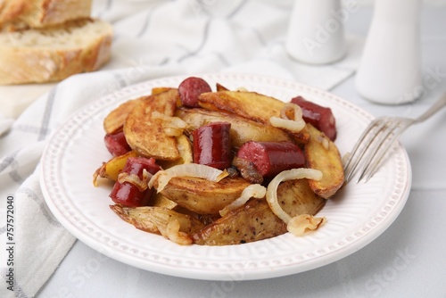 Delicious baked potato with thin dry smoked sausages and onion served on white table, closeup