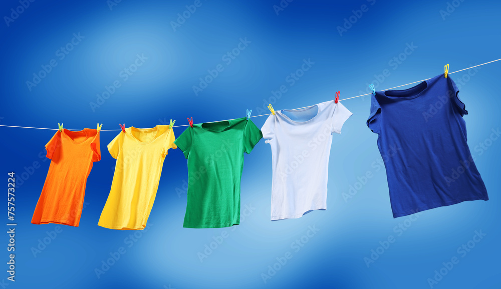 Colorful t-shirts drying on washing line against blue sky, banner design Colorful t-shirts drying on washing line against blue sky, banner design