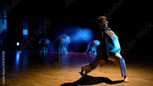 Fototapeta Naklejka Na Ścianę i Meble -  They demonstrate various dance moves. A group of girls are dancing on stage under beautiful lighting. Framed on a green gradient background, the focus is on. A group of attractive young girls is