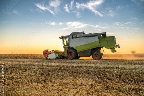 Combine harvester at work in a field during a picturesque sunset