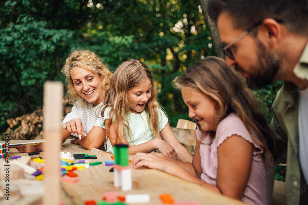 A happy family is playing with educational toy in nature on picnic. A happy family is playing with educational toy in nature on picnic.