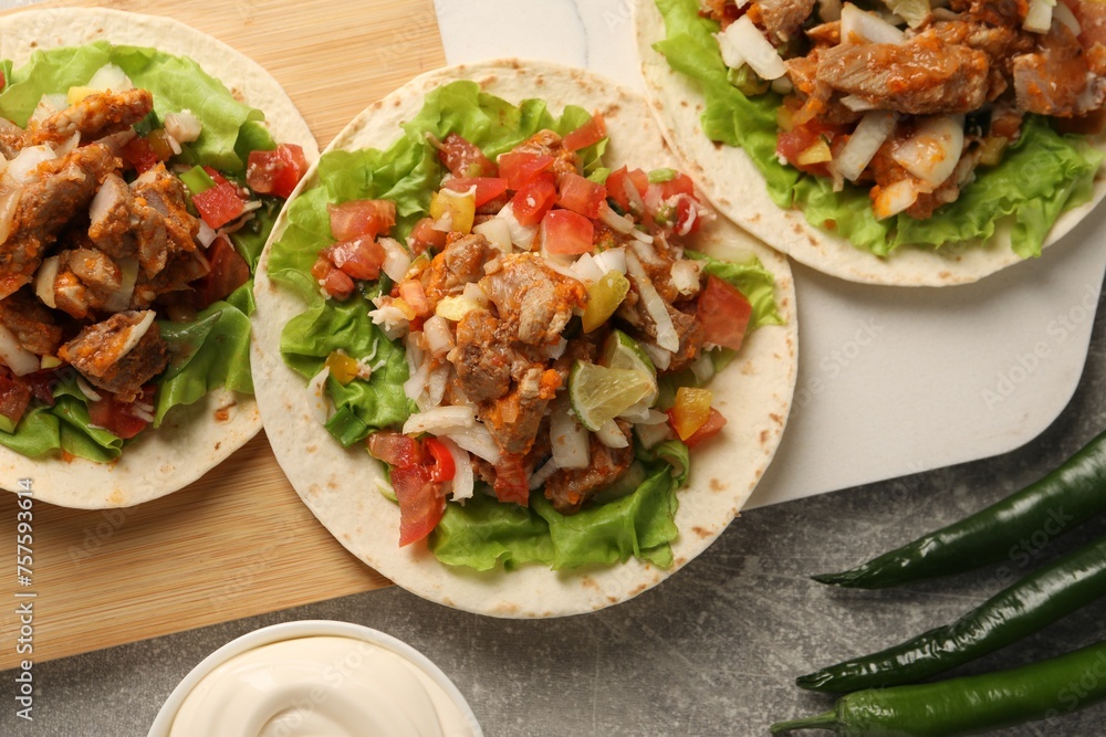 Delicious tacos with vegetables and meat on grey textured table, flat lay Delicious tacos with vegetables and meat on grey textured table, flat lay