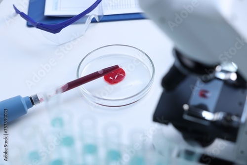 Dripping blood sample onto Petri dish on white table in laboratory  closeup