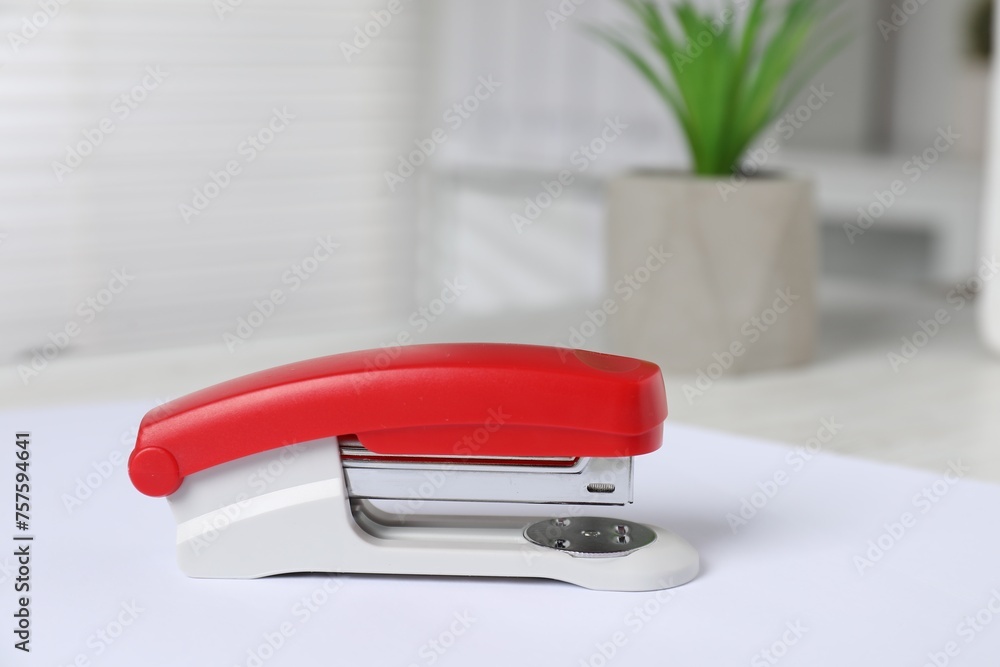 Bright stapler and paper on table indoors, closeup Bright stapler and paper on table indoors, closeup