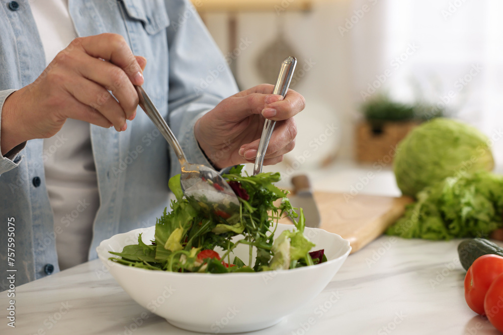 Woman making salad at white marble table in kitchen, closeup Woman making salad at white marble table in kitchen, closeup