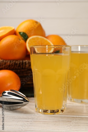 Tasty freshly made orange juice on white wooden table