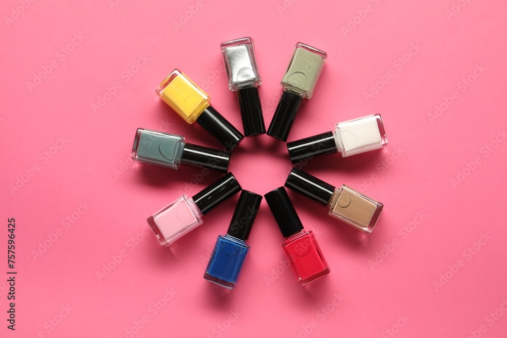 Obraz premium Bright nail polishes in bottles on pink background, flat lay