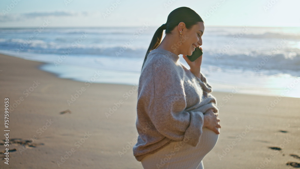 Future mother talking smartphone walking beach close up. Pregnant woman calling 