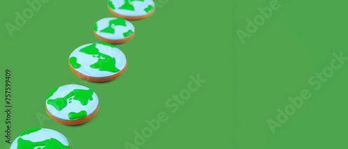 Earth Day concept. Сookies in shape of Earth on green backdrop. Banner image.
