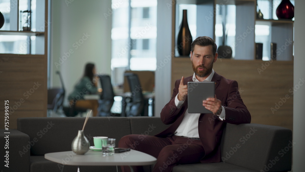 Naklejka premium Serious lawyer talking digital discussion at modern hall. Man holding tablet