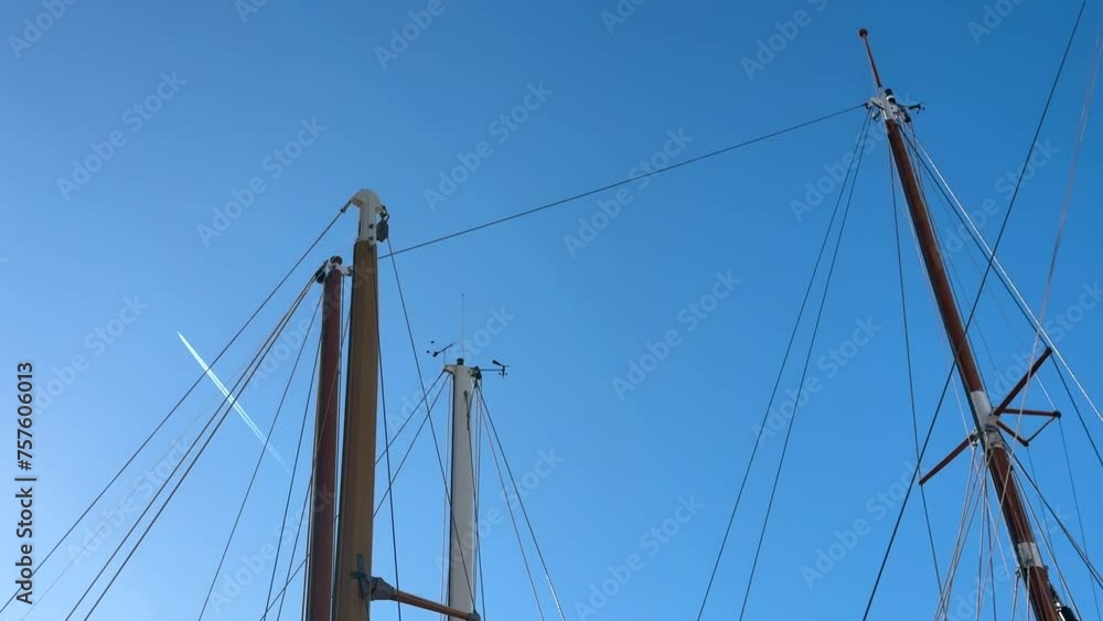 Sailboats at marina and flying passenger airplane in sunny blue sky Sailboats at marina and flying passenger airplane in sunny blue sky