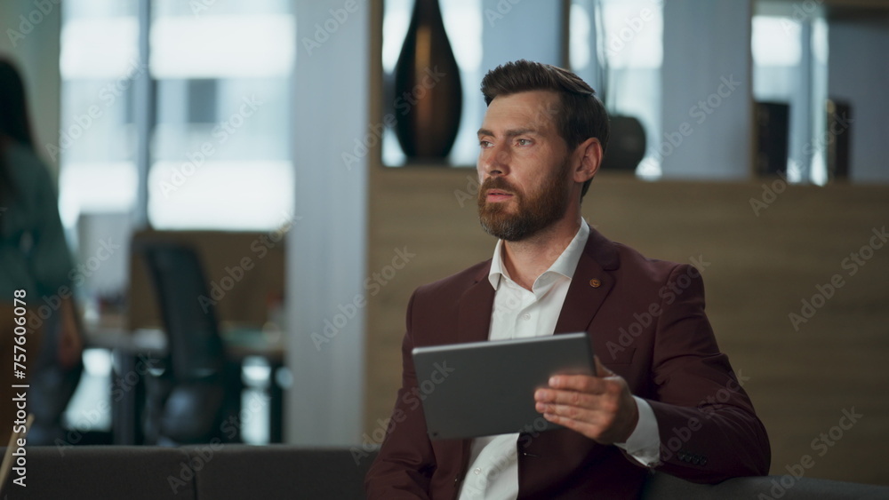 Sad millioner holding tablet computer in comfortable office interior cabinet. Sad millioner holding tablet computer in comfortable office interior cabinet.