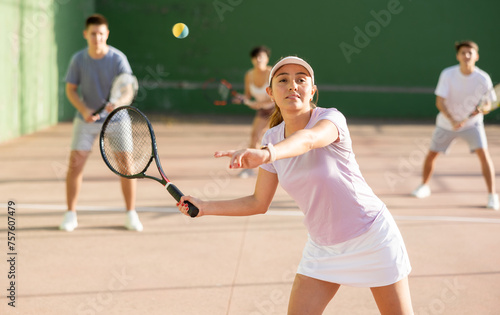 Latin woman serving ball during frontenis game outdoors. Woman playing pelota on outdoor fronton. © JackF