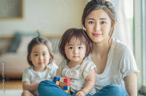 Young Japanese woman in jeans and shirt  sitting with child and colorful blocks  light room  affectionate  space for text.
