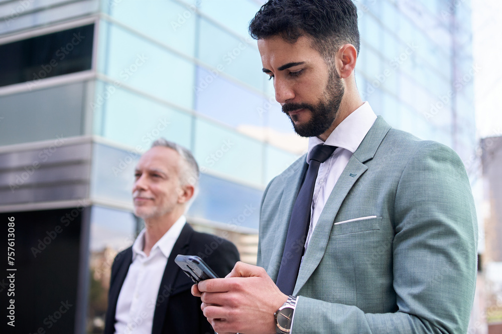 Attractive suit young business man typing concentrated on cell phone outside office building. Formal Caucasian professional staff bearded standing using mobile with blurred background for copy space Attractive suit young business man typing concentrated on cell phone outside office building. Formal Caucasian professional staff bearded standing using mobile with blurred background for copy space