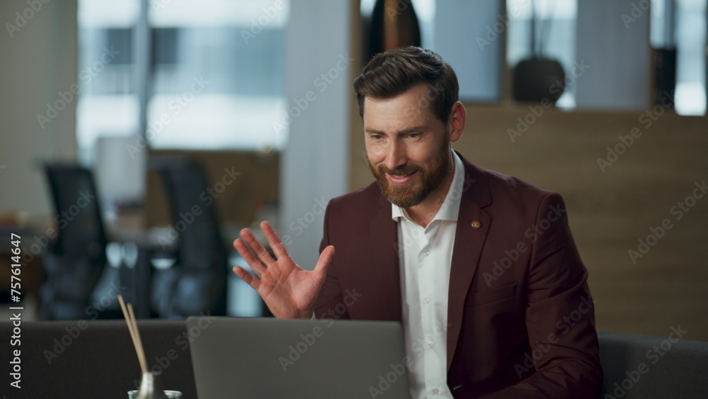 Cheerful man greeting hand video chat using modern laptop at office desk closeup
