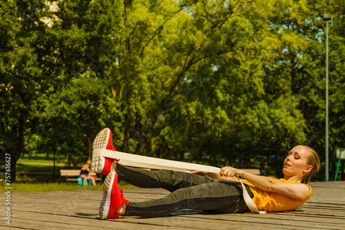 Girl doing exercises outdoor, using fit band. photo