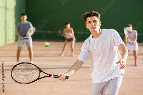 Young man playing frontenis on outdoor pelota court during training. Man playing Basque pelota speciality. © JackF