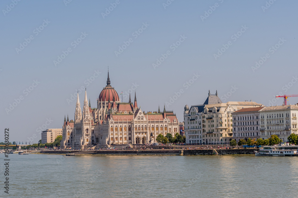 View of the Hungarian Parliament Building beside the Danube River on a sunny day in Budapest, Hungary