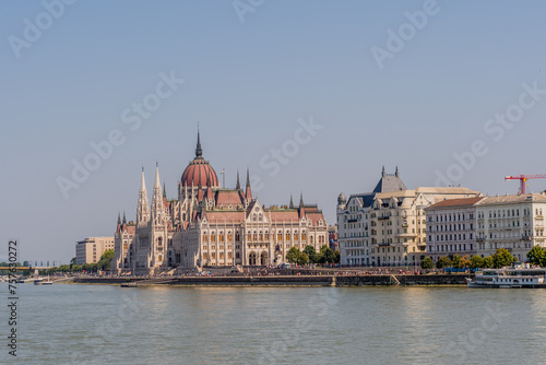 View of the Hungarian Parliament Building beside the Danube River on a sunny day in Budapest, Hungary © aminkorea