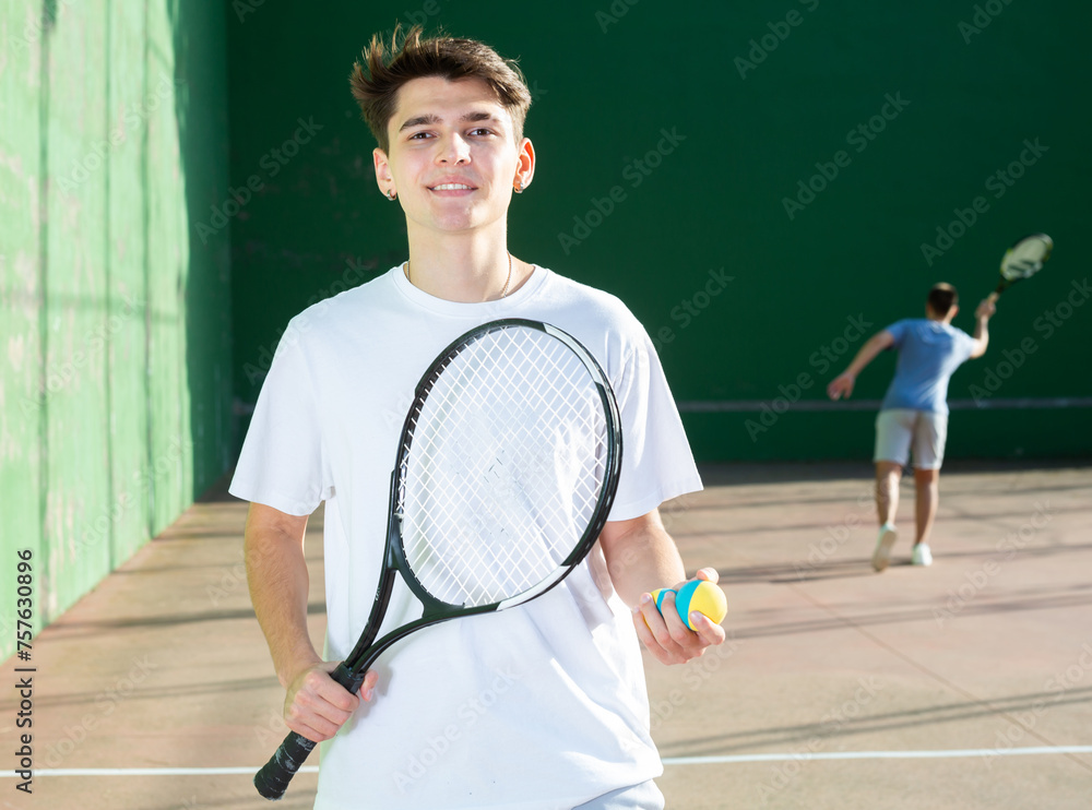 Portrait of cheerful caucasian man frontenis player in outdoor court