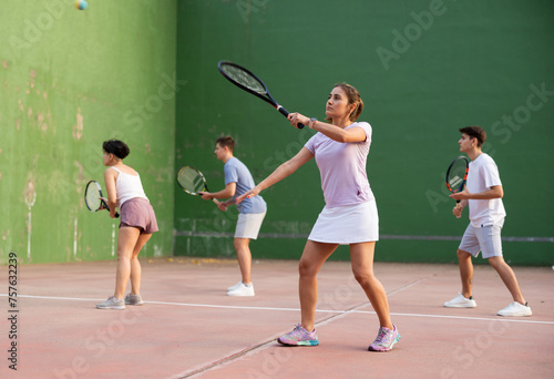 Focused woman playing frontenis with partners at sunny day, healthy lifestyle concept © JackF