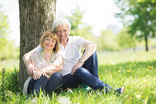 elderly people hugging next to a tree