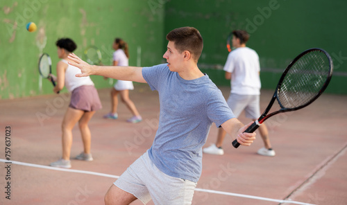 Focused man playing frontenis with partners at sunny day, healthy lifestyle concept © JackF