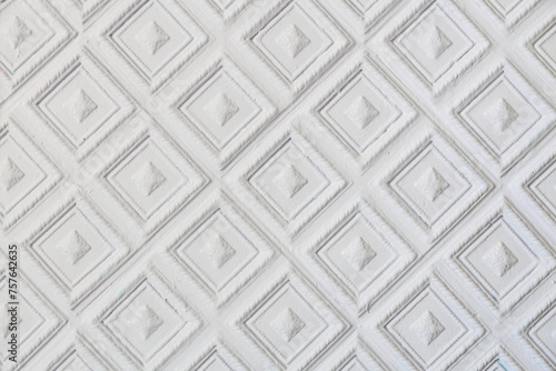 The image is a close up of a white wall with a diamond pattern