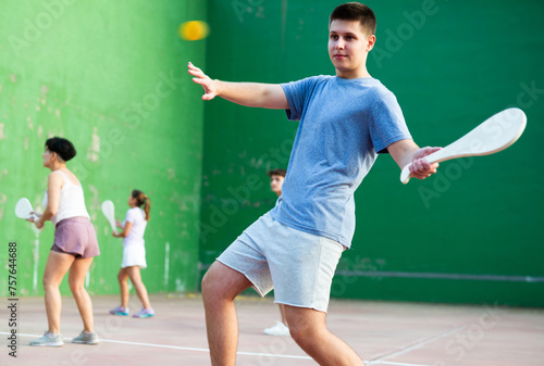 Young man playing Basque pelota on outdoor pelota court during training. Teenager playing pelota speciality with wooden paleta. © JackF