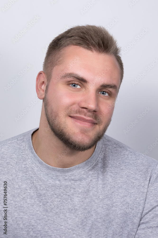 A smiling young blond man with a beard wearing a gray shirt A smiling young blond man with a beard wearing a gray shirt