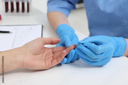 Laboratory testing. Doctor taking blood sample from patient at white table in hospital, closeup
