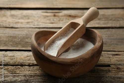 Baking powder in bowl and scoop on wooden table, closeup