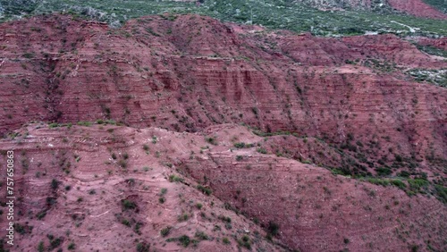 Sedimentary rock cliffs rich in iron oxide glow red, Argentina aerial photo