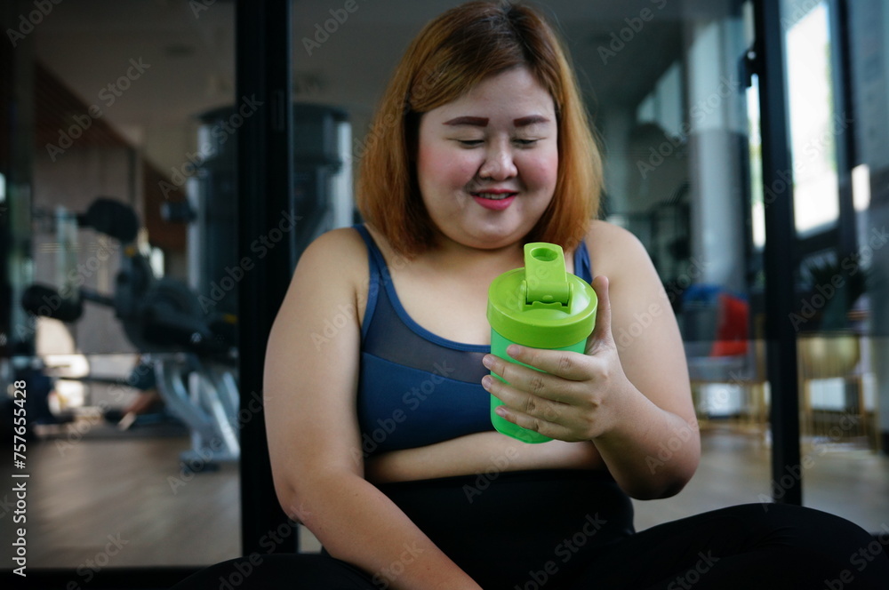 Woman in sports clothing holding shaker with protein cocktail at gym. Woman in sports clothing holding shaker with protein cocktail at gym.