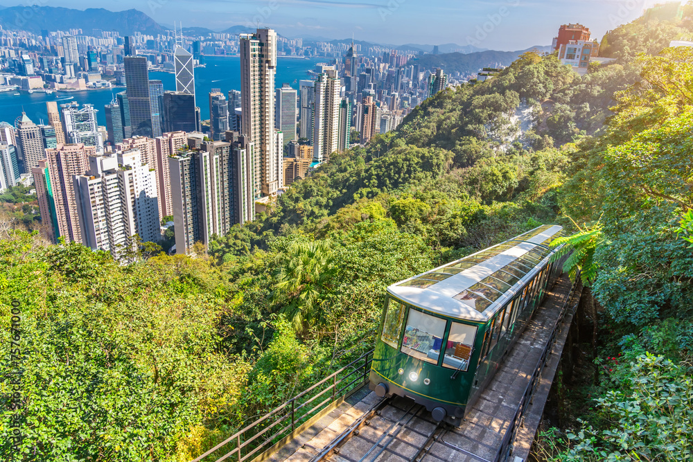 Naklejka premium The famous green tram on the slope of Victoria Peak in Hong Kong passes, lifting visitors to the observation deck at the top