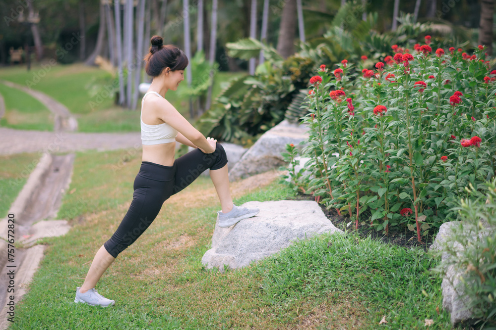 Fototapeta premium Sportswoman. Fit young Asian woman with sportswear stretching muscle in park before running and enjoying healthy outdoor. Fitness runner girl in public park. Wellness being concept
