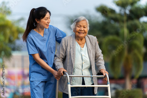 caregiver nurse support senior woman walking with walker in park