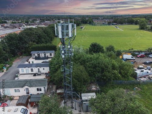 Aerial view of a telecommunication tower of 4G and 5G cellular against a green field