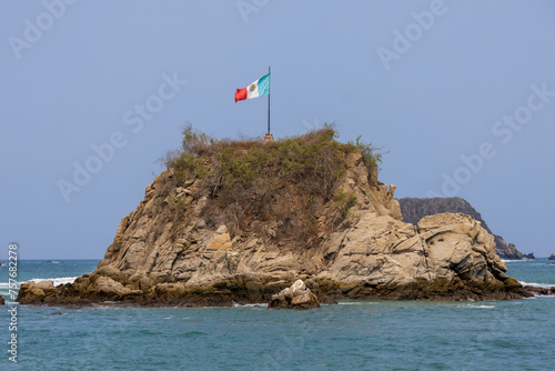 Mexican Flag over rocks at the beach in Huatulco, Oaxaca, Mexico (ID: 757682278)