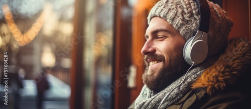 A man with a beard and headphones is smiling and looking out of a window. He seems happy and relaxed, enjoying the view of the landscape outside photo